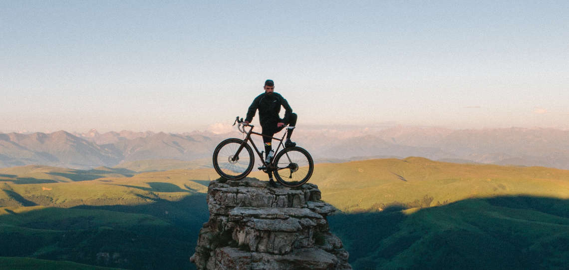 Mann steht mit einem Fahrrad auf einem Berg Mann steht mit einem Fahrrad auf einem Berg
