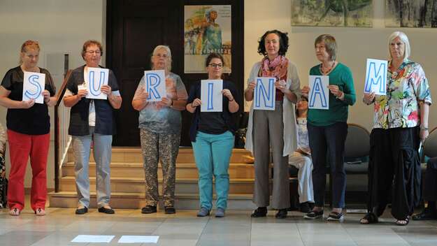 Frauen halten die Buchstaben S-U-R-I-N-A-M hoch