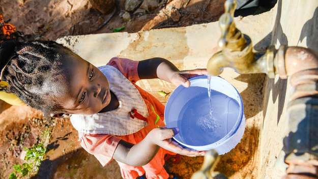 Mädchen holt Wasser in einem Eimer