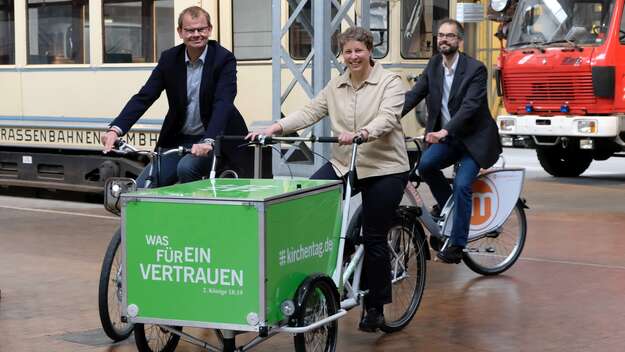 Stefanie Rentsch (mitte), Studienleiterin des Kirchentages, Axel Rolfsmeier (li.), Projektleiter der Kooperation Nachhaltigkeit, und Christof Hertel (re.) von der Stabsstelle Umwelt des Kirchentages stellen die Lastenräder vor, die auf dem Kirchentag in D