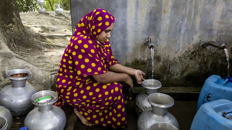 Frauen warten mit ihren Krügen darauf, an der Wassseraufbereitungsanlage Wasser zu holen