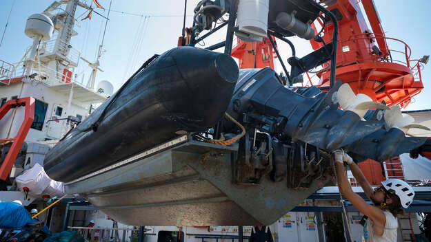 Bootsmann Allesandro leitet das Verladen der RIB-Schnellboote für die Rettungseinsätze auf dem Meer
