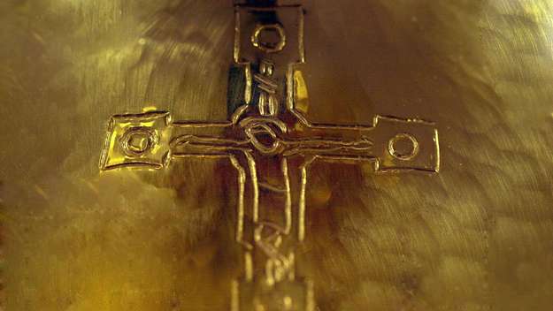 Ein goldener Abendmahlskelch, in den ein Kreuz graviert ist