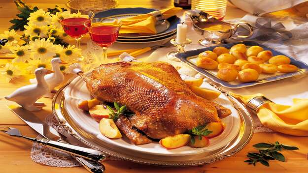 Festlich angerichtete Martinsgans mit Kartoffeln, Äpfeln und Wein