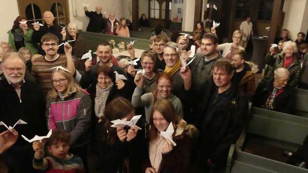 Gottesdienstbesucher mit im Gottesdienst gefalteten Origami-Friedenstauben