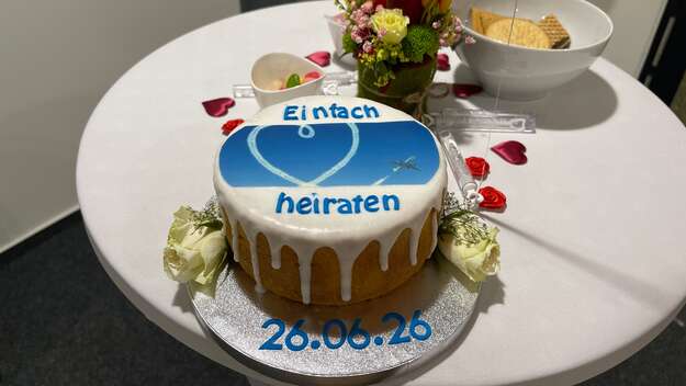 Eine Torte mit weißem Zuckerguss und blauer Aufschrift: Einfach heiraten.-Auf dem silbernen Teller steht das Datum 26.06.26