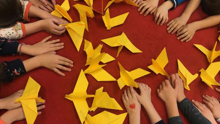 Kinder der Klasse Rot (Jahrgang 1-3) der Evangelischen Grundschule Mahlow mit ihren gelben Friedenstauben auf rotem Untergrund