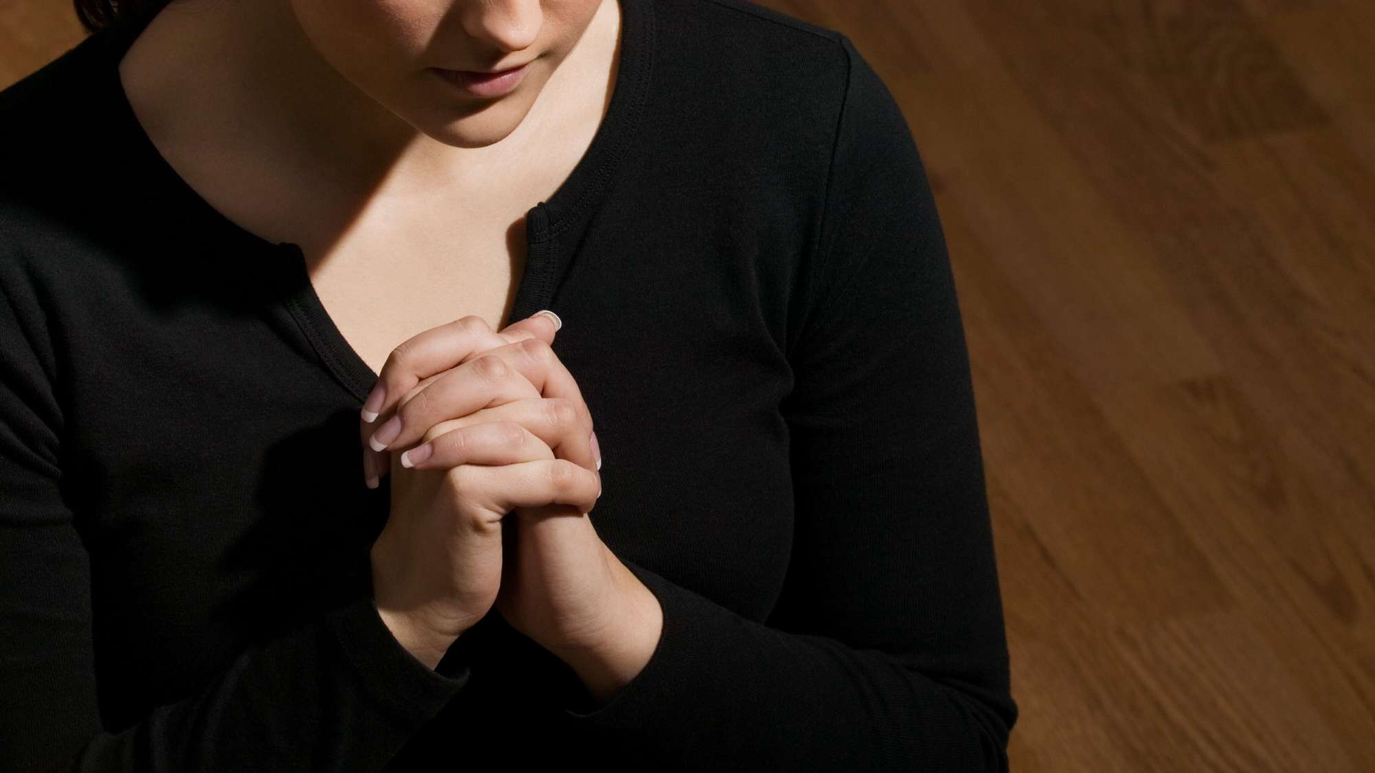 Frau betet mit gefalteten Händen vor der Brust