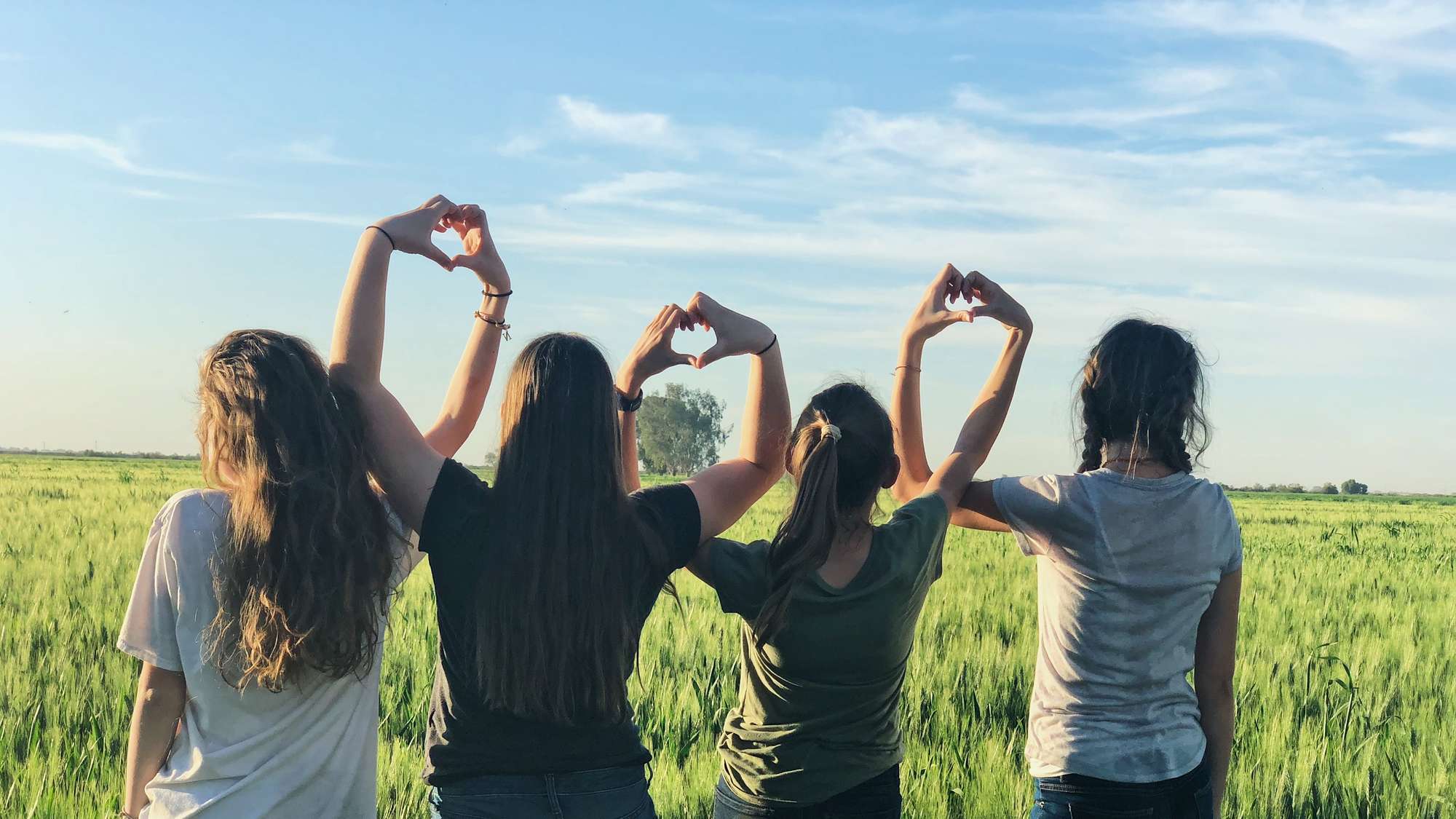 Vier Mädchen machen Herz-Zeichen mit ihren Händen