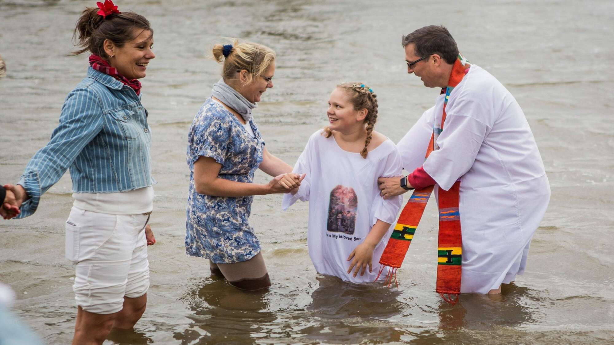 Pastor mit einem Mädchen und zwei Frauen beim Taufritual in der Elbe in Hamburg