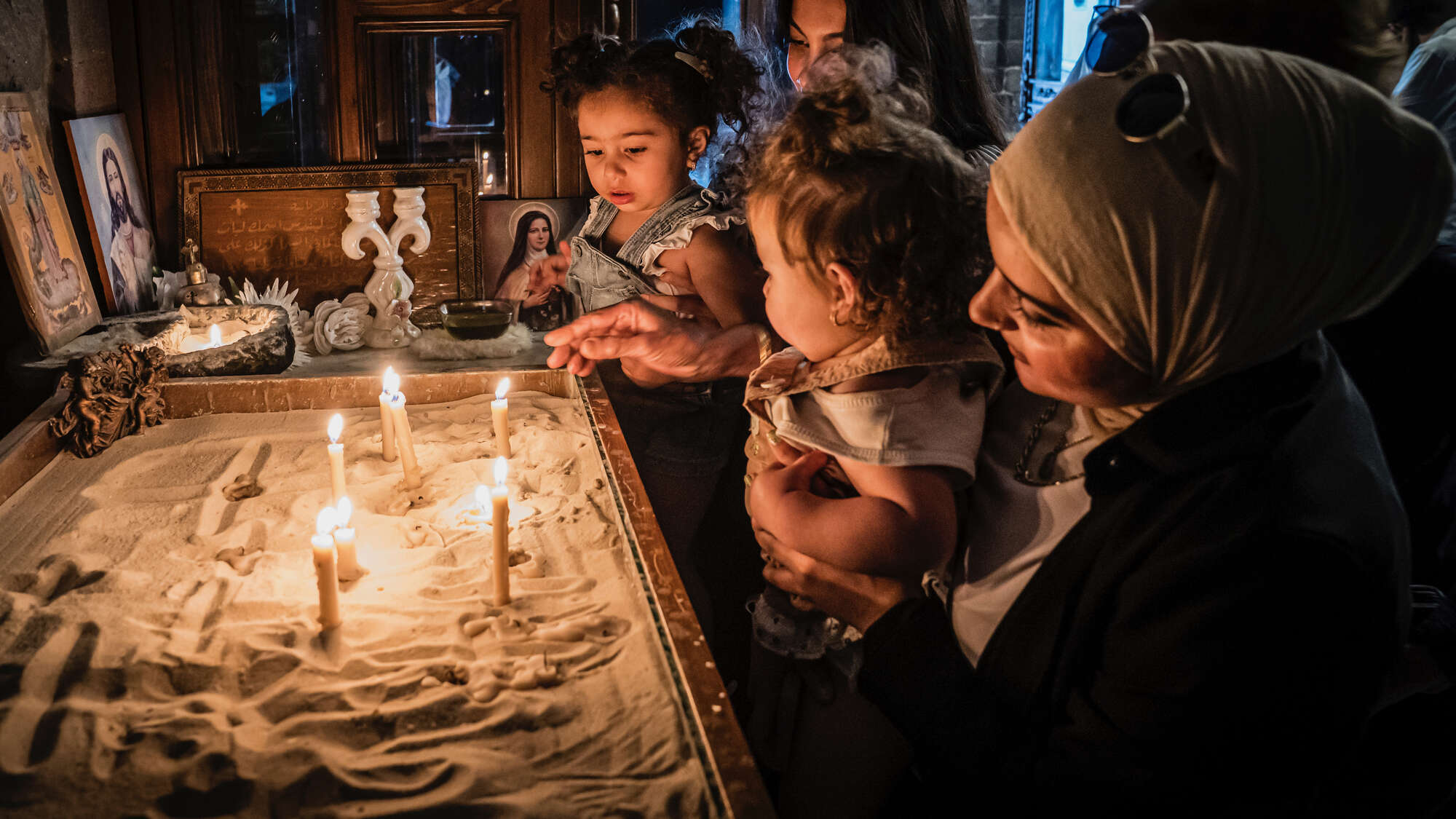 In einer Kirche in Homs, Syrien: Eine Frau (Christin) zeigt ihrer Freundin (Muslimin) diese Kirche, gemeinsam mit ihren Kindern zünden sie Kerzen an. In einer Kirche in Homs, Syrien: Eine Frau (Christin) zeigt ihrer Freundin (Muslimin) diese Kirche, gemeinsam mit ihren Kindern zünden sie Kerzen an.
